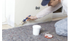 man painting the corner of a wall with white paint inside a home