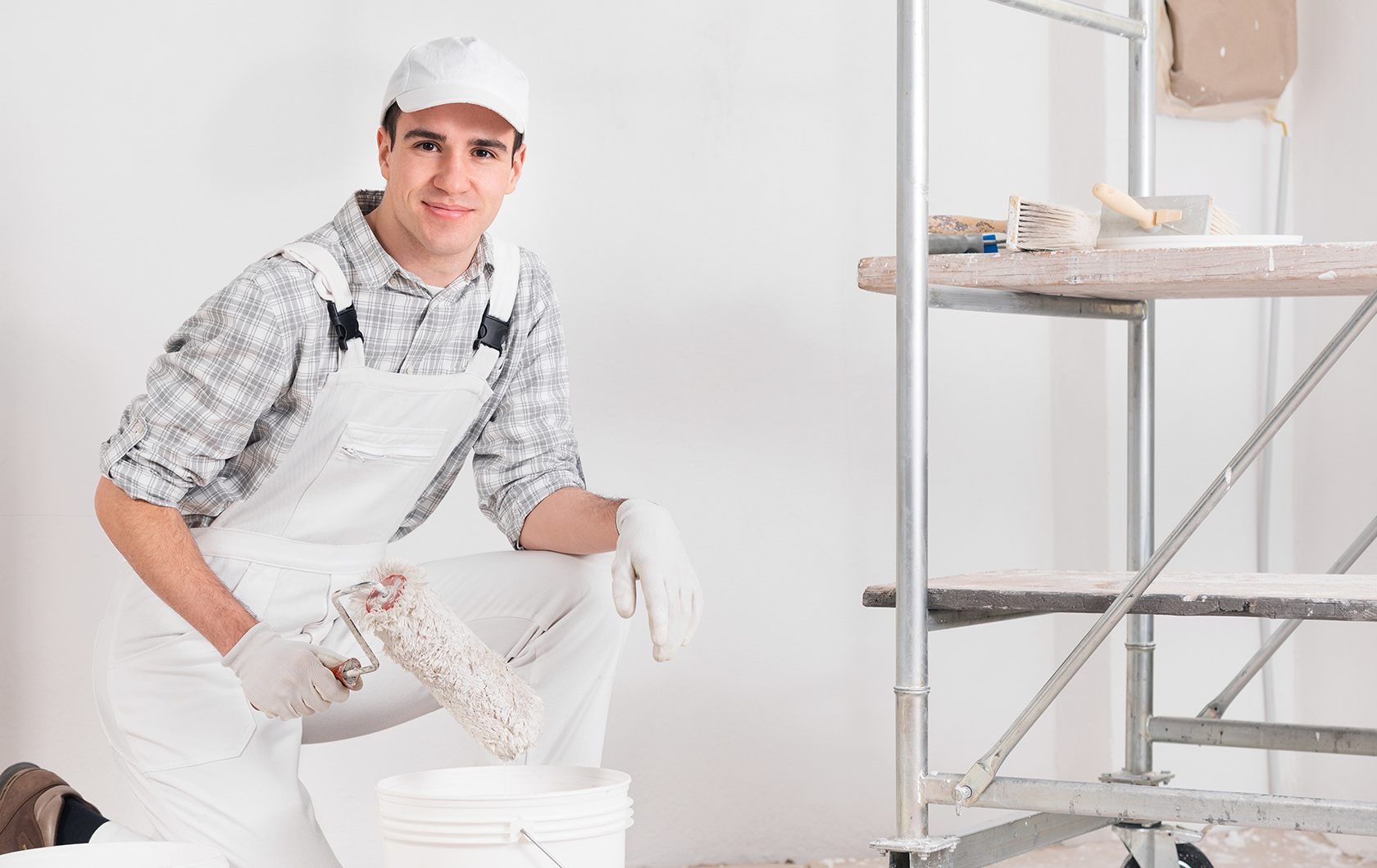 man with painting overalls holding a paint roller