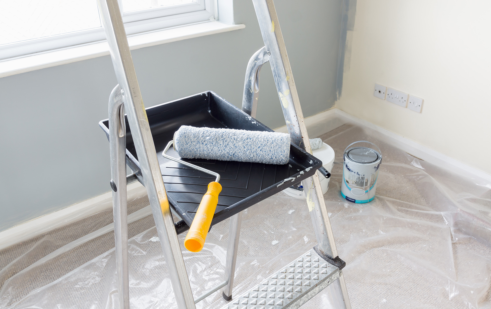 paint roller on a pair of steps in a room ready to paint