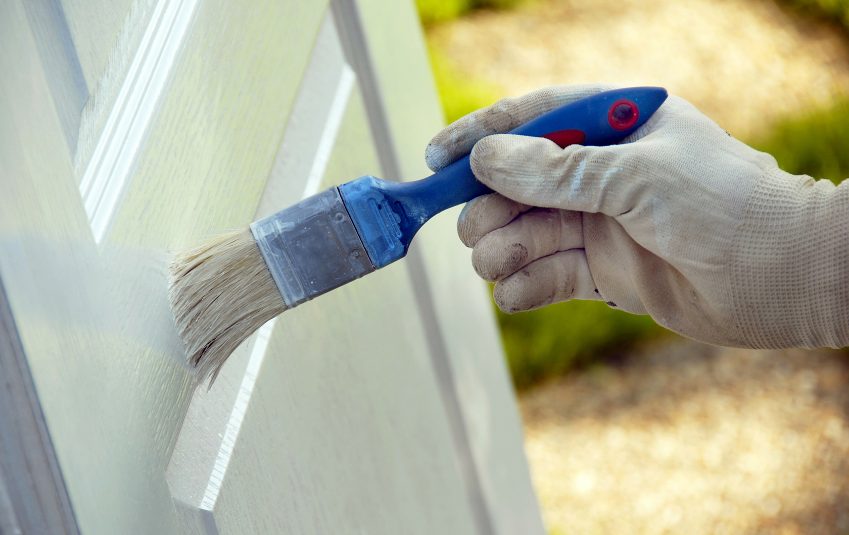 person painting a door with white paint