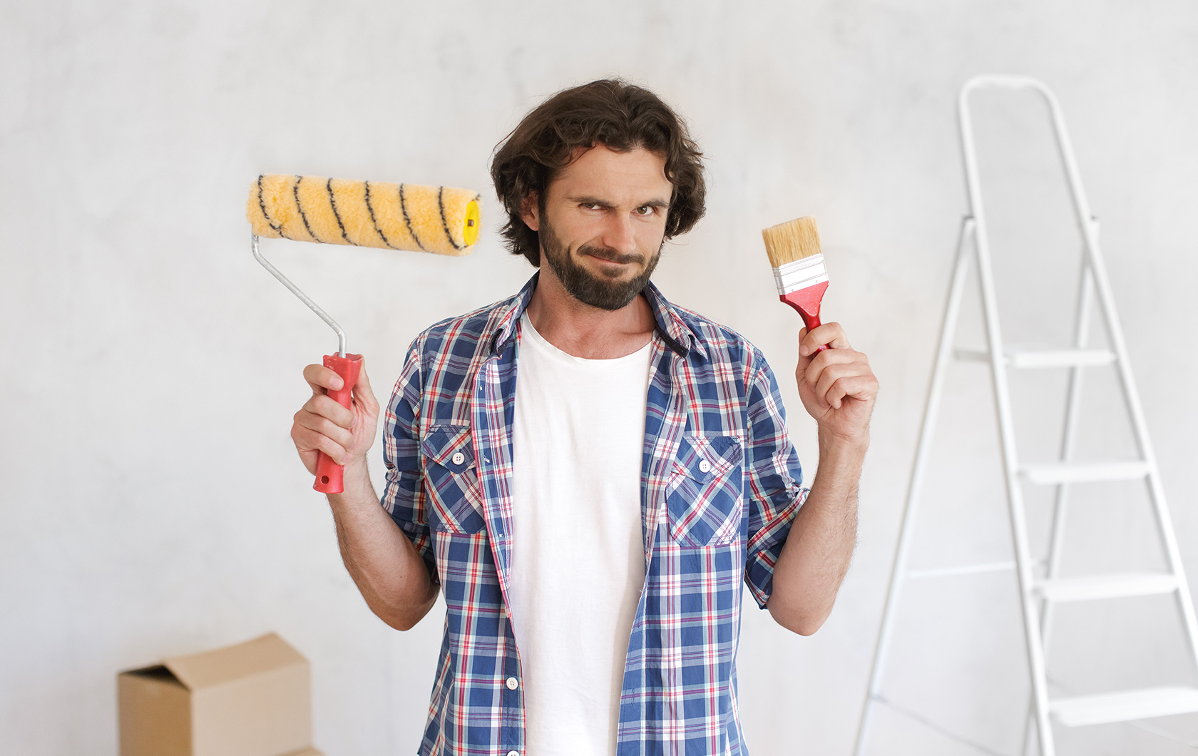 man holding a paint brush and paint roller