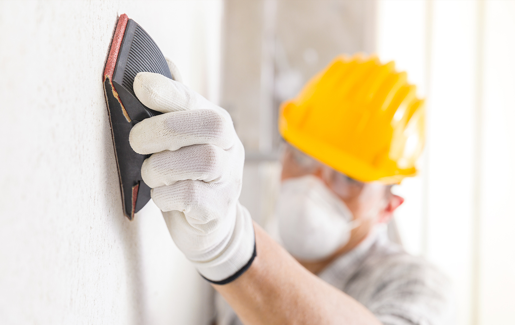 man sanding a wall before painting