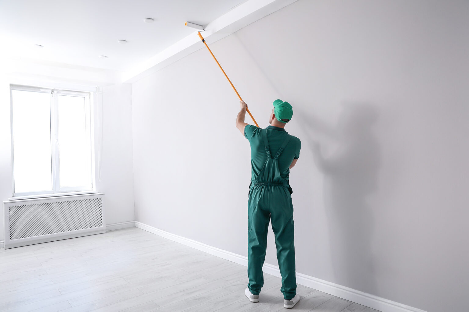 a man painting a ceiling with a extension pole roller