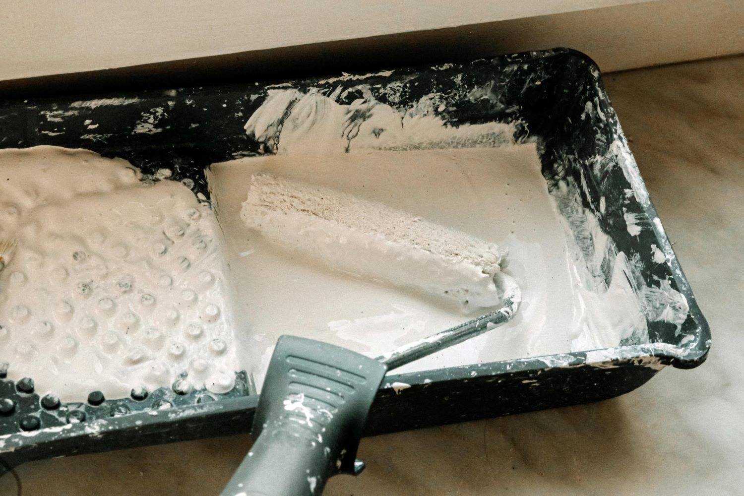 white paint on a paint roller and paint tray for painting walls and ceilings